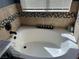 A bathtub with decorative tile surround and black hardware offers a relaxing experience at 2747 Sandalwood Ave, Henderson, NV 89074