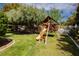 Backyard playground with a slide, swings, and climbing structure, nestled under mature trees at 3007 La Mesa Dr, Henderson, NV 89014