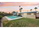 Inviting backyard with a sparkling pool, lush green lawn, and mature palm trees set against a colorful sky at 3140 Sundown Dr, Las Vegas, NV 89169