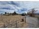 Wide exterior shot of the home with a long driveway, desert landscaping, and a chainlink fence at 3451 Ramona Ln, Pahrump, NV 89048