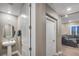 Well-lit bathroom featuring a pedestal sink, round mirror, and a storage closet, creating a serene and inviting atmosphere at 4193 Solace St # 4193, Las Vegas, NV 89135
