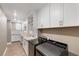 Bright laundry room with modern cabinets, solid surface counters, sink, tile backsplash, and black front load washer and dryer at 4193 Solace St # 4193, Las Vegas, NV 89135