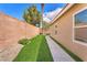 A backyard with a narrow strip of artificial grass and a brick wall on one side at 4878 Friar Tuck Ave, Las Vegas, NV 89130