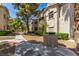Exterior condo view with a sidewalk leading past lush trees, next to a grill at 6480 Annie Oakley Dr # 814, Las Vegas, NV 89120