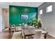 Dining area with a large wooden table, stylish seating, and an eye-catching green accent wall at 669 Assurance Pl, Henderson, NV 89011