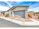 Home exterior with a two-car garage, desert landscaping, and brick driveway at 669 Assurance Pl, Henderson, NV 89011
