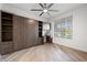 A cozy bedroom features light wood-look floors, a ceiling fan, and a built-in Murphy bed with desk and shelving at 7058 W Camero Ave, Las Vegas, NV 89113