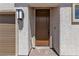 This welcoming front entrance features an elegant brown door, set within a stucco facade and cobblestone walkway, highlighting charm and style at 7482 Lodano Ave, Las Vegas, NV 89113