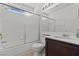 Clean bathroom with shower-tub combo, white tiles, a vanity and large mirror at 7954 Kentshire Dr, Las Vegas, NV 89117