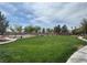 Expansive community green space with walking path, mature trees, and a tennis court in the background at 8084 Celina Hills St, Las Vegas, NV 89131