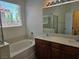 Bright bathroom with a soaking tub, double vanity, and natural light from a window at 9463 Jumping Frog Ct, Las Vegas, NV 89147