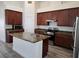 Kitchen island with stone countertops, stainless steel appliances, and dark wood cabinets at 9463 Jumping Frog Ct, Las Vegas, NV 89147