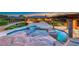 Lavish backyard with pool, rock features, and jacuzzi tub at dusk at 9920 Rancho Destino Rd, Las Vegas, NV 89183