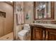 Stylish bathroom featuring a dark wood vanity, marble countertop, decorative mirror, and a tiled walk-in shower at 9920 Rancho Destino Rd, Las Vegas, NV 89183