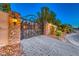 Ornate iron gate with stone pillars and landscape lighting at 9920 Rancho Destino Rd, Las Vegas, NV 89183