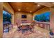 Outdoor kitchen and dining area featuring a stone wall, stainless steel appliances, and tiled flooring at 9920 Rancho Destino Rd, Las Vegas, NV 89183