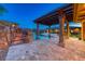 Stunning pool area featuring a rock waterfall, lush landscaping, and covered patio with elegant columns at 9920 Rancho Destino Rd, Las Vegas, NV 89183