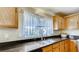 Kitchen featuring wood cabinets, dark countertops, and a window with lace curtains at , Las Vegas, NV 89148