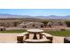 Landscaped backyard with a stone table and seating, complemented by manicured plants and beautiful mountain views at 1348 Basin Vw, Mesquite, NV 89034