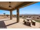 Covered outdoor patio area with a table, bench and views of the desert landscape at 1348 Basin Vw, Mesquite, NV 89034