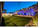 Expansive backyard featuring vibrant turf, complimented by an eye-catching retaining wall with captivating lighting accents at 395 Prairie Sun St, Las Vegas, NV 89138