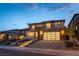 Elegant two-story home featuring a modern garage door, desert landscaping, and inviting front entrance with lit stairs at 395 Prairie Sun St, Las Vegas, NV 89138
