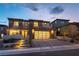 Elegant two-story home featuring a modern garage door, desert landscaping, and inviting front entrance with lit stairs at 395 Prairie Sun St, Las Vegas, NV 89138