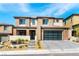 Elegant two-story home featuring a modern garage door, desert landscaping, and inviting front entrance with lit stairs at 395 Prairie Sun St, Las Vegas, NV 89138