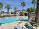 Community pool with lounge chairs and a cabana, surrounded by palm trees and black metal fencing at 10001 Peace Way # 2277, Las Vegas, NV 89147