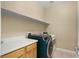 Laundry room equipped with modern washer and dryer, complemented by a counter and overhead shelf offering efficiency at 10013 Scenic Walk Ave, Las Vegas, NV 89149