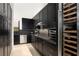 Modern kitchen features sleek, black cabinetry, stainless steel appliances, and a built-in wine fridge at 10756 Steel Ridge Ct, Las Vegas, NV 89135