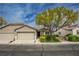 Inviting single-story home featuring a two-car garage, mature landscaping, and a well-maintained front yard at 10980 Ampus Pl, Las Vegas, NV 89141