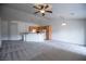 Open-concept living area showcasing a kitchen bar, neutral paint, modern lighting, and comfortable carpeting at 10980 Ampus Pl, Las Vegas, NV 89141