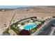 Aerial shot of a community pool area with a spa, cabanas, and landscaping surrounded by desert terrain at 10980 Ampus Pl, Las Vegas, NV 89141