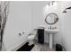 Modern half bathroom featuring a pedestal sink, round mirror, and wood-style tile floor at 12 Tatahatso Point St, Henderson, NV 89011
