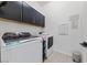 Well-lit laundry room featuring black cabinets, modern appliances, and complementary wall decor at 12 Tatahatso Point St, Henderson, NV 89011
