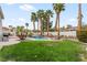 The backyard boasts a sparkling pool, lush lawn, and towering palm trees, perfect for outdoor activities at 1430 October Oak Ave, Las Vegas, NV 89123