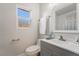 A cozy bathroom featuring gray vanity, white fixtures, and a bright window view at 1720 Hassett Ave, Las Vegas, NV 89104