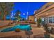 Backyard featuring a pool with rock features, ambient string lights, outdoor dining, and covered patio with comfortable seating at 2749 Carolina Blue Ave, Henderson, NV 89052