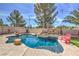 Backyard with a pool and beautiful rock waterfall feature, lounge chairs, and mature landscaping at 2749 Carolina Blue Ave, Henderson, NV 89052