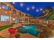 The backyard has a private pool, rock features, string lights and seating area, creating an oasis for relaxation and entertainment at 2749 Carolina Blue Ave, Henderson, NV 89052