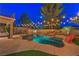 Backyard with a freeform pool, a rock waterfall, mature landscaping, string lights and an outdoor dining area at 2749 Carolina Blue Ave, Henderson, NV 89052