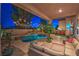 Backyard oasis has a freeform pool with rock waterfall, comfortable seating, string lights, and lush landscaping at 2749 Carolina Blue Ave, Henderson, NV 89052