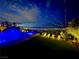 Inviting pool area with a captivating city view at night, enhanced by stylish string lights and lush landscaping at 286 Shaded Canyon Dr, Henderson, NV 89012