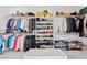 Organized walk-in closet featuring custom shelving, a variety of shoes and clothing, and a tufted ottoman at 286 Shaded Canyon Dr, Henderson, NV 89012