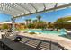Stunning backyard with a pool, spa, pergola covered patio, lush landscaping, and play area at 3458 W Agate Ave, Las Vegas, NV 89139