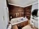 Simple bathroom offering a soaking tub, pedestal sink, and wood-paneled accent wall at 3491 S Bridle Way, Crystal, NV 89020