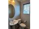 Well-lit bathroom with a pedestal sink, toilet, window, and tiled flooring at 355 Gracious Way, Henderson, NV 89011