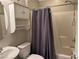 Bathroom featuring tiled shower with caddy and seat, toilet, sink, and a grey shower curtain at 355 Gracious Way, Henderson, NV 89011