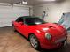 Garage interior with a red convertible parked, featuring an EV charger and overhead lighting at 355 Gracious Way, Henderson, NV 89011